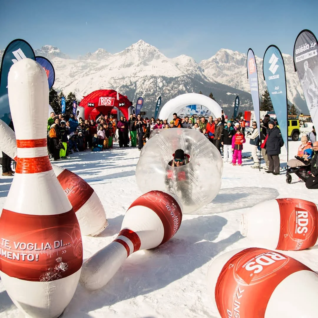 Pubblico e gioco interattivo RDS sulla neve, con le Dolomiti sullo sfondo.